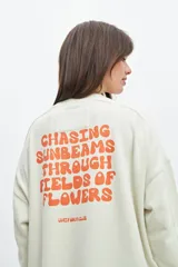 Buzo celeste de corte holgado con cuello redondo y mangas largas. Estampado en la espalda con la frase "Chasing sunbeams through fields of flowers".