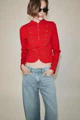 Chaquetas de cuello redondo y manga larga, de color rojo. Cuenta con detalle de botones dorados frontales y en los puños, con cierre delantero con corchetes ocultos.