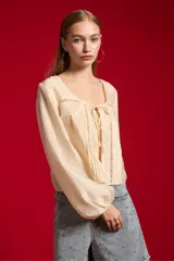 Blusa de lyocell color natural, holgada y de manga larga, con cuello redondo, detalles de encaje y lazo para anudar en el frente.