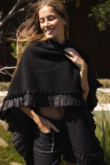 Ruana artesanal de lana merino en color marrón oscuro, con diseño tejido de textura marcada, detalles de volados laterales y flecos en el ruedo.