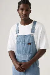 Jardinera de jean en corte holgado, con tirantes ajustables, múltiples bolsillos funcionales y cierre de botones laterales.