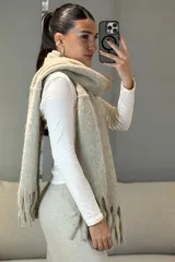 Bufanda de tejido grueso y suave, color blanco, con diseño de flecos en los extremos.