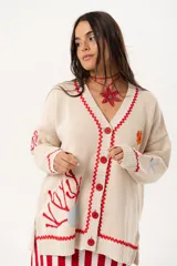 Saco oversize tejido con ilustraciones inspiradas en corales, peces, estrellas de mar y tortugas. Presenta galón picot en rojo en cartera y puños, y botones a tono.