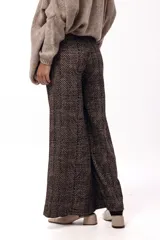 Pantalón de tiro medio-alto con silueta amplia y caída fluida. Presenta un diseño con estampado de espiga en tonos marrones y negros, bolsillos laterales y corte recto.