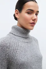 Sweater gris melange de tejido buclé con cuello alto y mangas largas.