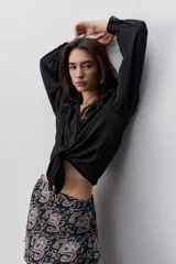 Camisa de manga larga color beige con cuello clásico y botonadura frontal. Presenta mangas con volumen sutil, puños abotonados y una silueta amplia de caída fluida.