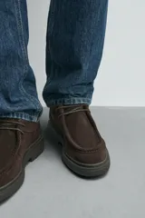 Zapato de cordones con diseño tipo mocasín, confeccionado en piel con acabado de serraje en color marrón. Presenta detalle de costura en el empeine y suela de goma texturizada a tono.