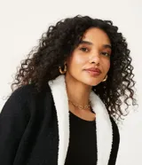 Chaqueta de tricot color negro con interior de pelo sintético blanco, corte recto, manga larga y bolsillos frontales. Marca Blue Steel.