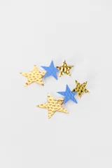 Par de aros colgantes con diseño de tres estrellas de diferentes tamaños y texturas. Combina estrellas doradas con acabado martillado y estrellas celestes con textura mate.