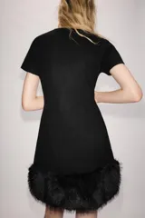 Vestido corto de punto color negro, con cuello redondo, manga corta y bajo con aplicación de pelo sintético a tono.