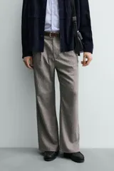 Pantalón relaxed fit color marrón con patrón de espiga, confeccionado en tejido con viscosa. Presenta pliegues frontales, bolsillos laterales y bolsillos traseros de vivo. Cierre frontal con cremallera y botón.