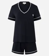 Conjunto de pijama compuesto por una remera de manga corta con escote en V y un short, ambos en color negro con detalles de vivos blancos en contraste. La remera cuenta con un bolsillo frontal pequeño.