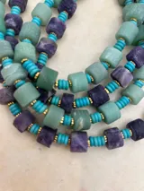 Collar de cuentas de piedra natural en tonos verde y lila, intercaladas con cuentas turquesas y detalles dorados.