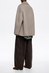 Chaquetón corto de corte recto confeccionado en lana doble faz, con doble botonadura frontal, cuello con solapa y manga larga. Presenta bolsillos en costura y barbuquejo en el cuello.