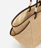 Bolso de playa tipo tote de paja natural con asas de cuero sintético marrón, forro interior y bolsillo interno.