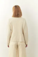 Cárdigan color crema de tejido de punto industrial con escote en V, combinación de puntos y botones decorativos en las mangas.