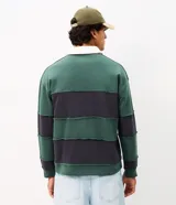 Remera tipo chomba de manga larga, con bloques de color en tonos verde y azul marino, cuello polo blanco y pequeño bordado en el pecho.