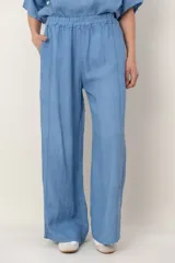 Pantalón de lino azul con cintura elástica, bolsillos laterales y detalle de alforzas verticales a los costados.