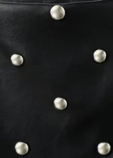 Minifalda de corte recto efecto piel, color negro, con diseño corto y adorno de tachuelas metálicas repartidas por la superficie. Cuenta con cierre de cremallera lateral y forro interior.
