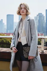 Cartera tipo sobre con estampado animal print de leopardo, con cierre superior y correa de cadena metálica negra.