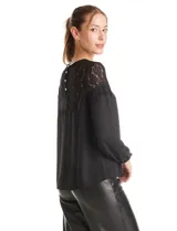 Blusa de gasa negra con canesú de encaje en el frente y la espalda, manga larga con puño elastizado y cierre de botones perlados en la espalda.