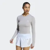 Remera de running manga larga Adidas, de corte ajustado y diseño cropped. Presenta cuello redondo, aberturas para los pulgares en los puños y logo de la marca reflectante en el pecho. Confeccionada con tecnología Climacool para la gestión de la humedad.