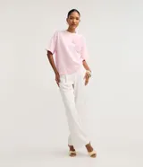 Blusa boxy de manga corta, confeccionada en algodón, con cuello redondo y detalles de flores de tejido aplicadas en el hombro y sisa.