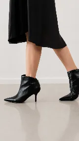 Bota corta de cuero con acabado metalizado plateado, punta fina y taco aguja de 8 cm.