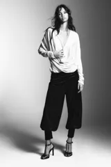 Pantalón negro de tiro bajo, confeccionado en terciopelo con pequeños puntos brillantes. Presenta cintura elástica con pliegues, caída ancha tipo baggy y puños ajustados en los tobillos.