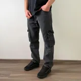 Pantalón jean cargo color negro con efecto lavado, de corte recto y bolsillos laterales con solapa en las piernas.
