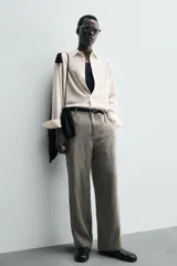 Camisa de hombre de corte relajado (relaxed fit) en tejido de mezcla de algodón y viscosa, color beige claro con finas rayas verticales. Presenta cuello italiano y manga larga con puño abotonado.