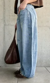 Jean de denim celeste de corte barrel, tiro bajo, con roturas y detalles desgastados en la rodilla.