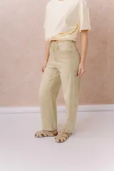 Jean de calce relajado y pierna amplia color beige, con tiro alto y detalle de recortes y costuras visibles.