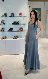 Vestido largo de paño gris con sutiles destellos brillantes, corte entallado en el torso con escote cuadrado y falda amplia con bolsillos laterales.