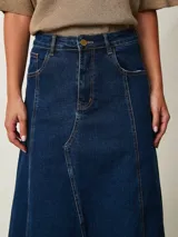 Pollera larga de denim azul con diseño de paneles, bolsillos delanteros y tajo frontal. Presenta terminación deshilachada en el ruedo.