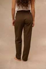Pantalón de vestir marrón de tiro alto, corte recto y pinzas en la parte delantera. Cuenta con presillas para cinturón y detalles ajustables con hebillas metálicas en los laterales de la cintura.
