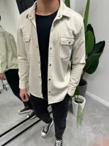 Sobrecamisa de gabardina color beige con cierre frontal de botones metálicos a presión, dos bolsillos frontales con solapa y diseño de canesú estilo western.