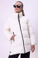 Campera puffer de corte oversize y largo medio, color blanco, con cuello alto, cierre frontal y aberturas laterales con botones a presión.