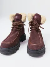 Borcegos de caña baja con diseño robusto, confeccionados en una combinación de gamuza y cuero sintético en tonos verde oliva. Presentan suela track de goma dentada en color suela, cordones al tono con ojalillos amarillos y cuello acolchado para mayor confort.