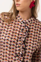 Camisa de gasa estampada traslúcida con diseño geométrico de rombos en tonos lila, naranja y negro. Tiene calce liviano y fluido, abotonado frontal y volado en la cartera.