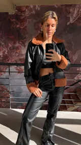 Campera negra de cuero sintético con cuello y puños de corderito color marrón.