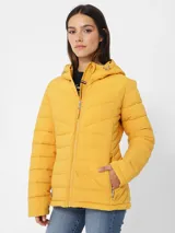 Campera amarilla acolchada con capucha, cierre frontal con cremallera, bolsillos laterales y logo de Tommy Hilfiger en el pecho.