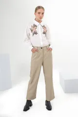 Pantalón de vestir color beige, de corte recto, con bolsillos laterales y traseros. Se ajusta a la cintura con cinturón de cuero marrón.
