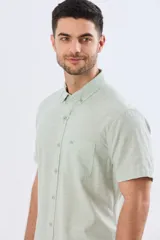 Camisa de manga corta confeccionada en mezcla de lino y algodón, color beige, con cuello camisero abotonado, bolsillo frontal en el pecho y cierre de botones.