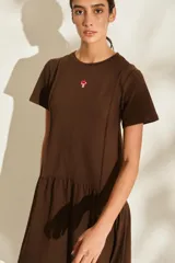 Vestido midi color crudo de manga corta, con corte en la cintura y falda holgada con volados y detalle de pequeño bordado de hongo en el pecho.
