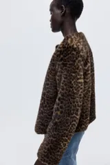 Campera de piel sintética con estampado de leopardo, cuello redondo y cierre frontal con botones. Presenta un diseño de corte recto y forro interior.