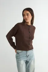 Cardigan de punto color marrón chocolate, con cuello redondo, cierre frontal de botones y diseño de costuras verticales visibles. Presenta puños y ruedo acanalados.