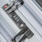 Valija de mano rígida de policarbonato color plateado, con diseño texturizado de líneas verticales, protectores en las esquinas y ocho ruedas giratorias multidireccionales. Cuenta con cierre y candado TSA integrado.