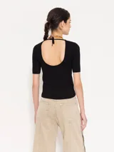 Top tejido en hilado frío color verde militar, con calce al cuerpo, mangas cortas y abertura en la espalda que se ata en el cuello.