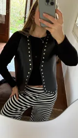Chaleco negro de ecocuero con tachas doradas.